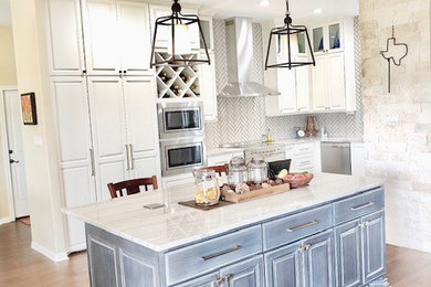 Large transitional l-shaped porcelain tile and brown floor kitchen pantry photo in Austin with an undermount sink, raised-panel cabinets, white cabinets, quartzite countertops, gray backsplash, subway tile backsplash, stainless steel appliances, an island and gray countertops