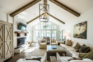 Inspiration for a mid-sized country formal and open concept dark wood floor and brown floor living room remodel in Atlanta with white walls, a standard fireplace, a brick fireplace and a wall-mounted tv