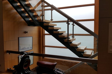 Large modern wood floating staircase in Chicago with open risers and glass railing.