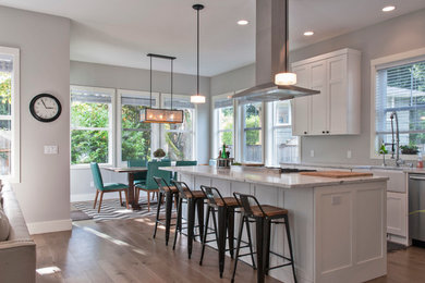 Inspiration for a large contemporary l-shaped medium tone wood floor kitchen remodel in Seattle with a farmhouse sink, shaker cabinets, white cabinets, marble countertops, stainless steel appliances and an island