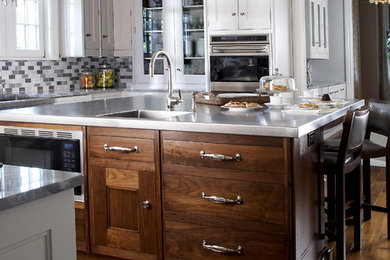 Example of a large classic u-shaped dark wood floor and brown floor kitchen design in New York with an integrated sink, beaded inset cabinets, white cabinets, marble countertops, multicolored backsplash, mosaic tile backsplash, stainless steel appliances and an island