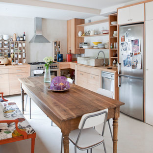 Foto de cocina comedor en L, ecléctica, de tamaño medio, con fregadero sobremueble, armarios con paneles empotrados, puertas de armario de madera clara, encimera de madera, salpicadero de metal, electrodomésticos de acero inoxidable y suelo de cemento