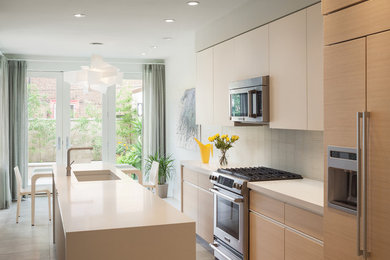 Inspiration for a contemporary galley eat-in kitchen in Philadelphia with a single-bowl sink, flat-panel cabinets, light wood cabinets, white splashback, stainless steel appliances, quartzite benchtops and glass tile splashback.