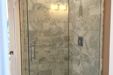 This is an example of a mid-sized transitional kids bathroom in Orlando with a corner shower, white tile, stone tile, beige walls and marble floors.