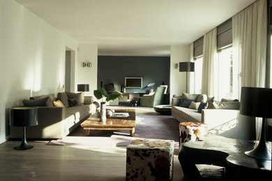 Foto de salón abierto actual grande con suelo de madera en tonos medios, televisor colgado en la pared y paredes blancas