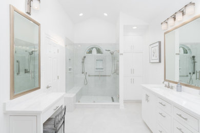 Design ideas for a medium sized contemporary ensuite bathroom in New Orleans with flat-panel cabinets, white cabinets, a walk-in shower, a two-piece toilet, white tiles, porcelain tiles, white walls, porcelain flooring, a submerged sink, engineered stone worktops, white floors, a hinged door, white worktops, a shower bench, double sinks, a built in vanity unit and a vaulted ceiling.