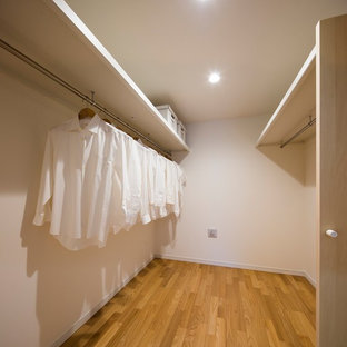 Small scandinavian u-shaped laundry cupboard in Tokyo with beaded cabinets, white cabinets, white walls, plywood flooring and brown floors.