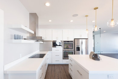 This is an example of a large contemporary l-shaped eat-in kitchen in Other with flat-panel cabinets, white cabinets, quartz benchtops, stainless steel appliances, dark hardwood floors, with island, brown floor and white benchtop.