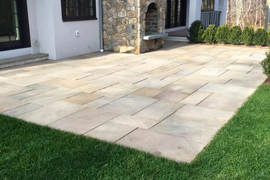 This is an example of a mid-sized transitional full sun backyard stone landscaping in New York with a fire pit.