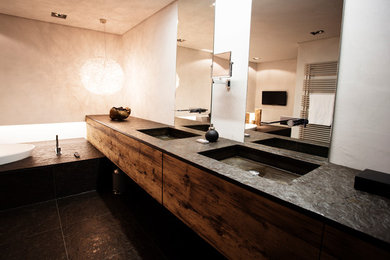 Mittelgroßes Uriges Badezimmer mit flächenbündigen Schrankfronten, hellbraunen Holzschränken, schwarzen Fliesen, weißer Wandfarbe, Schieferboden, integriertem Waschbecken und schwarzer Waschtischplatte in Stuttgart