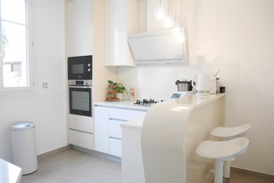 Exemple d'une cuisine encastrable chic en L fermée et de taille moyenne avec un évier 1 bac, un placard avec porte à panneau encastré, des portes de placard blanches, un plan de travail en quartz, une crédence blanche, une crédence en carreau de verre, un sol en carrelage de céramique, aucun îlot, un sol gris et un plan de travail blanc.