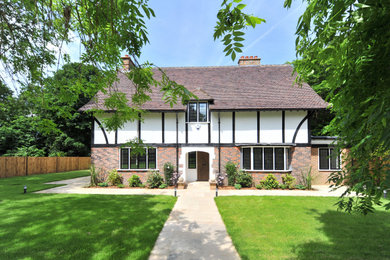 Ejemplo de fachada de casa blanca y marrón de estilo americano grande de tres plantas con tejado a dos aguas y tejado de teja de barro