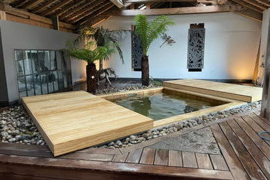 Ejemplo de piscina exótica pequeña rectangular con paisajismo de piscina y entablado