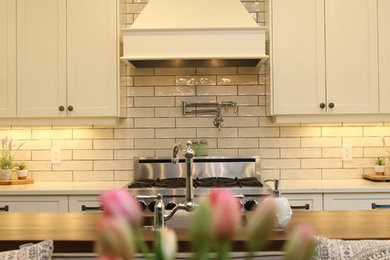 Inspiration for a cottage eat-in kitchen remodel in Other with a farmhouse sink, white cabinets, white backsplash, stainless steel appliances and an island