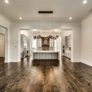 Großes, Offenes Mediterranes Wohnzimmer mit beiger Wandfarbe, dunklem Holzboden, Hängekamin, Kaminsims aus Stein und Wand-TV in Dallas