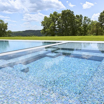 glass tile swimming pool + spa with perimeter overflow + granite decking