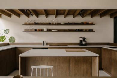 Photo of a large modern grey and brown u-shaped kitchen/diner in London with a single-bowl sink, flat-panel cabinets, dark wood cabinets, quartz worktops, black appliances, concrete flooring, an island, grey floors, grey worktops and exposed beams.