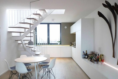 Offene Moderne Küche in L-Form mit Waschbecken, flächenbündigen Schrankfronten, weißen Schränken, Laminat-Arbeitsplatte, Küchenrückwand in Beige und hellem Holzboden in Berlin