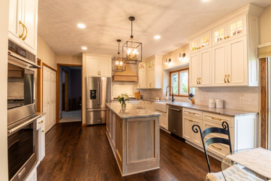 Mid-sized transitional dark wood floor and brown floor eat-in kitchen photo in Cleveland with a farmhouse sink, shaker cabinets, white cabinets, quartzite countertops, white backsplash, ceramic backsplash, stainless steel appliances, an island and gray countertops