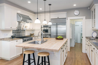 Inspiration for a transitional u-shaped medium tone wood floor and beige floor eat-in kitchen remodel in Philadelphia with a drop-in sink, shaker cabinets, white cabinets, granite countertops, white backsplash, stainless steel appliances and an island