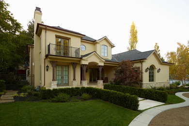 Inspiration for a mid-sized timeless beige two-story stucco gable roof remodel in Other