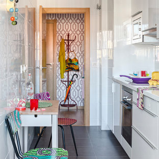 Удачное сочетание для дизайна помещения: маленькая линейная кухня в стиле фьюжн с обеденным столом, плоскими фасадами, белыми фасадами, белым фартуком, техникой из нержавеющей стали, полом из сланца и столешницей из акрилового камня без острова - самое интересное для вас