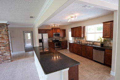 Inspiration for a large timeless galley porcelain tile kitchen remodel in Jacksonville with an undermount sink, recessed-panel cabinets, medium tone wood cabinets, granite countertops, brown backsplash, terra-cotta backsplash, stainless steel appliances and an island