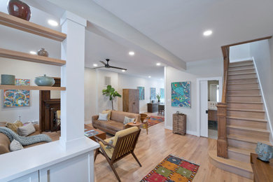 Example of a mid-sized mid-century modern open concept light wood floor and brown floor living room design in DC Metro with white walls, a standard fireplace and a wood fireplace surround