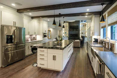 Example of a large trendy u-shaped dark wood floor open concept kitchen design in Detroit with a farmhouse sink, flat-panel cabinets, white cabinets, gray backsplash, matchstick tile backsplash, stainless steel appliances, an island and granite countertops