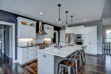 Example of an arts and crafts dark wood floor kitchen design in Other with a single-bowl sink, shaker cabinets, white cabinets, quartz countertops, white backsplash, subway tile backsplash, stainless steel appliances, an island and multicolored countertops