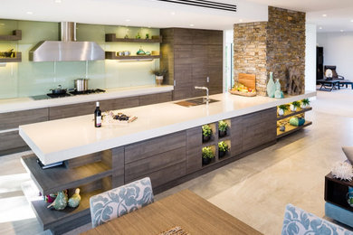 Large modern galley open plan kitchen in Melbourne with an undermount sink, flat-panel cabinets, dark wood cabinets, quartz benchtops, white splashback, glass sheet splashback, stainless steel appliances, porcelain floors, with island and white benchtop.