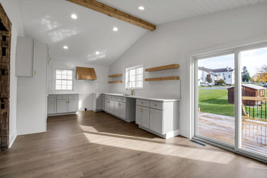 Mid-sized trendy l-shaped laminate floor, brown floor and shiplap ceiling kitchen photo in New York with a single-bowl sink, shaker cabinets, quartz countertops, white backsplash and white countertops