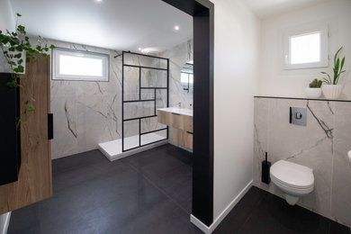Cette image montre une salle de bain principale design avec une douche ouverte, WC suspendus, des carreaux de céramique, un sol en carrelage de céramique, un plan vasque, un plan de toilette en surface solide, un sol noir, un plan de toilette blanc et meuble-lavabo suspendu.