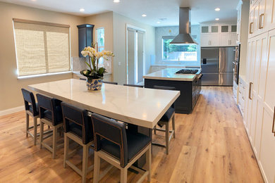 Design ideas for a large transitional l-shaped open plan kitchen in Sacramento with shaker cabinets, white cabinets, marble benchtops, with island, white benchtop, a farmhouse sink, grey splashback, subway tile splashback, stainless steel appliances, light hardwood floors and beige floor.