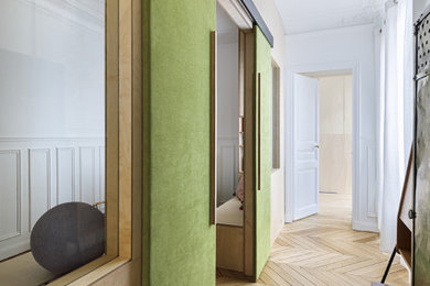 Imagen de habitación infantil unisex de 1 a 3 años contemporánea de tamaño medio con paredes blancas, suelo de madera clara y boiserie
