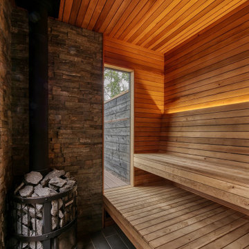 Beautiful outdoor wood burning sauna on a deck with a covered area and built-ins