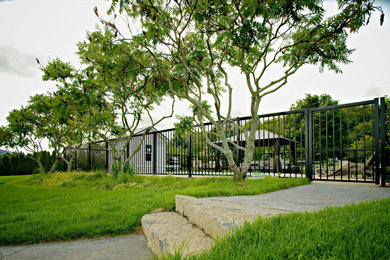 Imagen de piscina alargada grande rectangular en patio trasero con paisajismo de piscina y losas de hormigón