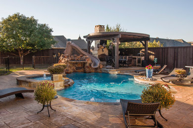Large country backyard custom-shaped natural pool in Dallas with stamped concrete and a hot tub.
