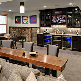 Photo of a medium sized traditional walk-out basement in Minneapolis with grey walls, carpet, a standard fireplace and a stone fireplace surround.