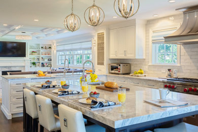 Inspiration for a large transitional u-shaped dark wood floor, brown floor and coffered ceiling open concept kitchen remodel in New York with a drop-in sink, recessed-panel cabinets, white cabinets, marble countertops, white backsplash, marble backsplash, stainless steel appliances, an island and white countertops