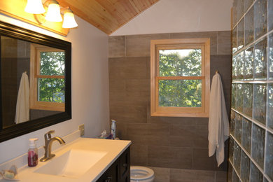 Inspiration for a mid-sized timeless master gray tile and porcelain tile gray floor and porcelain tile bathroom remodel in Other with a two-piece toilet, white walls, recessed-panel cabinets, black cabinets, an integrated sink, solid surface countertops and white countertops