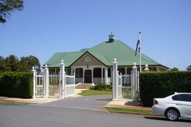 This is an example of a large traditional two-storey beige house exterior in Brisbane with wood siding, a gable roof and a metal roof.