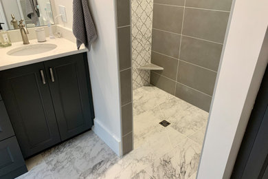 This is an example of a medium sized classic ensuite bathroom in Other with flat-panel cabinets, grey cabinets, a built-in shower, grey tiles, porcelain tiles, grey walls, porcelain flooring, a submerged sink, engineered stone worktops, grey floors, an open shower, white worktops, a wall niche, double sinks and a built in vanity unit.