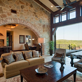 Design ideas for an expansive mediterranean formal open plan living room in Austin with beige walls, travertine flooring, a standard fireplace, a stone fireplace surround and a concealed tv.