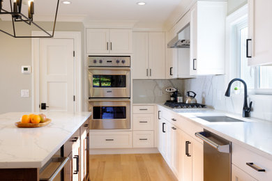 Mid-sized transitional l-shaped light wood floor eat-in kitchen photo in New York with an undermount sink, recessed-panel cabinets, white cabinets, quartz countertops, white backsplash, quartz backsplash, stainless steel appliances, an island and white countertops