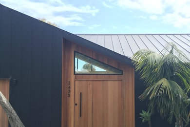 Ejemplo de fachada de casa negra moderna de tamaño medio de dos plantas con revestimiento de metal, tejado a la holandesa y tejado de metal
