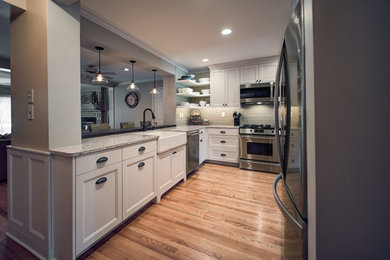 Design ideas for a small transitional u-shaped open plan kitchen in Boston with a farmhouse sink, white cabinets, quartzite benchtops, glass tile splashback, stainless steel appliances, recessed-panel cabinets, a peninsula, multi-coloured benchtop, brown floor, grey splashback and medium hardwood floors.