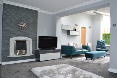 This is an example of a small contemporary open concept living room in Manchester with a library, grey walls, carpet, a standard fireplace and a built-in media wall.