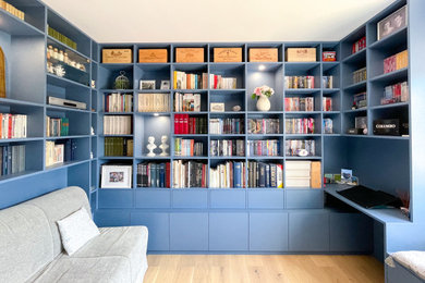 Aménagement d'un bureau moderne de taille moyenne avec une bibliothèque ou un coin lecture, un mur bleu, parquet clair, aucune cheminée, un bureau intégré et un sol beige.