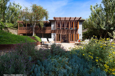 Mid-sized eclectic gray two-story stucco exterior home photo in Los Angeles with a hip roof